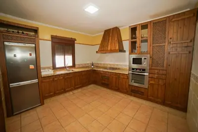 a large kitchen with wooden cabinets and stainless steel appliances at Casa Ana Mari in Conil de la Frontera