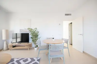 a living room with a table and chairs and a tv at APARTOYOU Apartments - Oasis El Puerto in El Puerto de Santa María