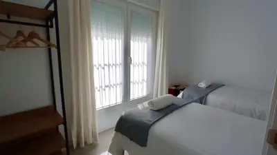 a bedroom with two beds and a window at El Patio de mama Carmen by RentCadiz in El Puerto de Santa María