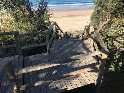 a wooden staircase leading to a beach with the ocean at El Patio de mama Carmen by RentCadiz in El Puerto de Santa María