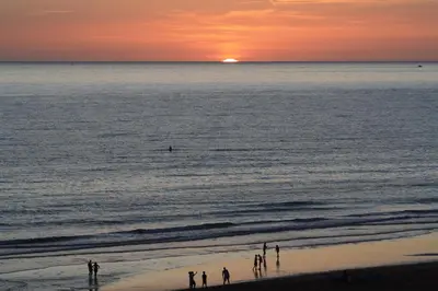 a group of people standing on the beach at sunset at El Patio de mama Carmen by RentCadiz in El Puerto de Santa María