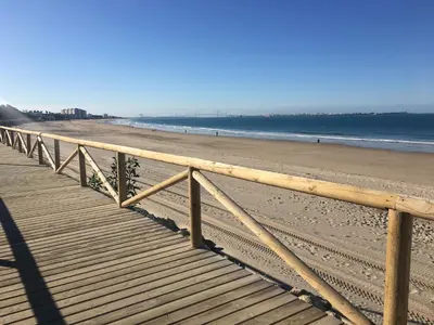 a wooden boardwalk stretches out into the beach at El Patio de mama Carmen by RentCadiz in El Puerto de Santa María