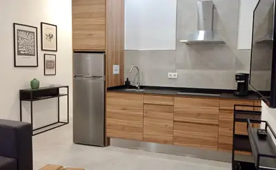 a kitchen with a stainless steel refrigerator and wooden cabinets at El Patio de mama Carmen by RentCadiz in El Puerto de Santa María