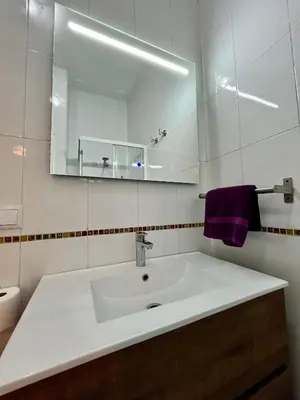 a bathroom with a sink with a mirror and purple towel at Villa María Cádiz centro, 