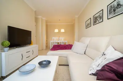 a living room with a white couch and a tv at Sibs Sanlucar RIOMAR-Renovado Centrico vistas in Sanlúcar de Barrameda