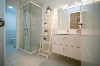 a white bathroom with a sink and a shower at Sibs Sanlucar RIOMAR-Renovado Centrico vistas in Sanlúcar de Barrameda