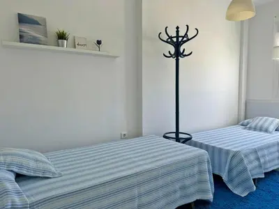 two beds in a white room with a blue carpet at Apartamento Cielo in El Puerto de Santa María