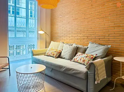 a couch in a living room with a brick wall at Ámbar Loft Grupo AC Gestion in Cádiz