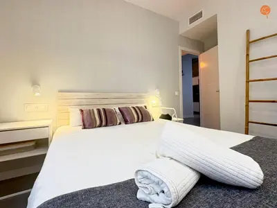a bedroom with a white bed with a towel on the floor at Ámbar Loft Grupo AC Gestion in Cádiz