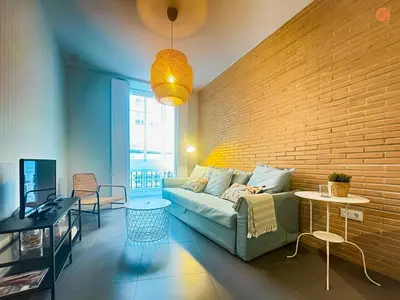 a living room with a couch and a brick wall at Ámbar Loft Grupo AC Gestion in Cádiz