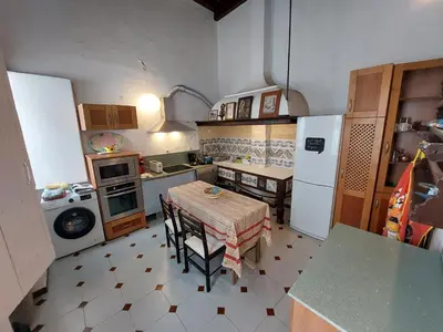a small kitchen with a table and a refrigerator at Casa Madre Gelart Patrimonio Gaditano del siglo XIX in San Fernando