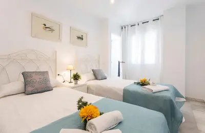 a white bedroom with two beds with flowers on them at Vistahermosa 2 Rooms Piscina in El Puerto de Santa María