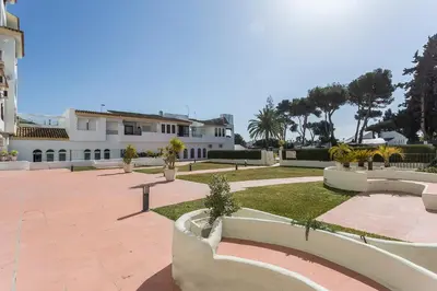 a courtyard with benches and a building with palm trees at Vistahermosa 2 Rooms Piscina in El Puerto de Santa María