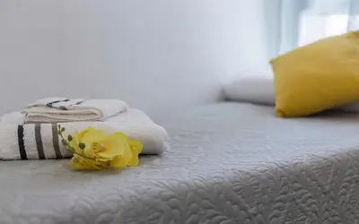 a bed with towels and yellow flowers on it at Apartamentos Collado Playa Valdelagrana in El Puerto de Santa María