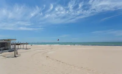 a person is flying a kite on the beach at Apartamentos Collado Playa Valdelagrana in El Puerto de Santa María