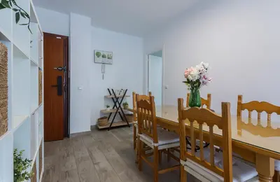 a dining room with a table and chairs and a vase of flowers at Apartamentos Collado Playa Valdelagrana in El Puerto de Santa María