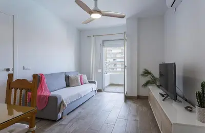 a living room with a couch and a flat screen tv at Apartamentos Collado Playa Valdelagrana in El Puerto de Santa María