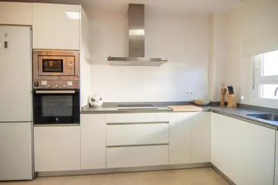 a kitchen with white cabinets and a stove top oven at Casa PLAYA FONTANILLA in Conil de la Frontera