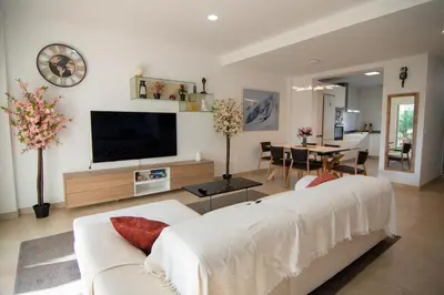 a living room with a white couch and a tv at Casa PLAYA FONTANILLA in Conil de la Frontera