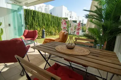 a wooden table with a vase of flowers on a patio at Casa PLAYA FONTANILLA in Conil de la Frontera