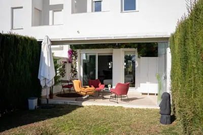 a patio with chairs and a table and an umbrella at Casa PLAYA FONTANILLA in Conil de la Frontera