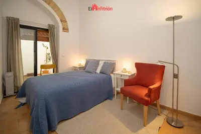 a bedroom with a bed and a chair and a lamp at El Anfitrión - Palacio XVIII in Sanlúcar de Barrameda