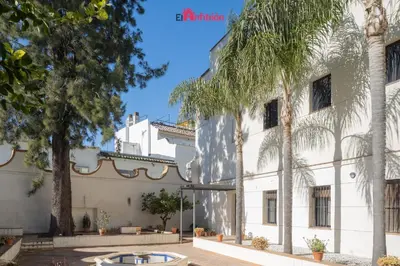 an exterior view of a building with palm trees at El Anfitrión - Palacio XVIII in Sanlúcar de Barrameda