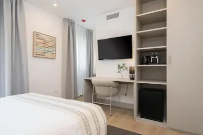 a bedroom with a bed and a desk and a tv at La Caleta QE Hotels in Cádiz