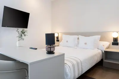 a bedroom with a bed with a desk and a tv at La Caleta QE Hotels in Cádiz