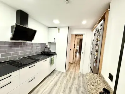 a kitchen with white cabinets and a tv on the wall at alsur by Staycare in Jerez de la Frontera