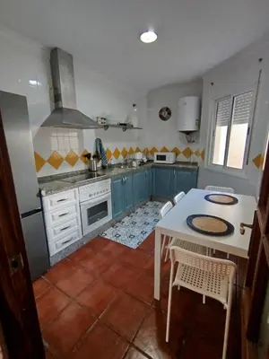 a kitchen with blue cabinets and a table with chairs at Brisa&Mar, con Posibilidad de Parking in Chipiona