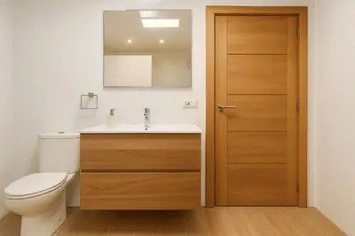 a bathroom with a toilet and a sink and a wooden door at Check-in autónomo Centro Histórico Todo a pie Ideal para parejas in Jerez de la Frontera