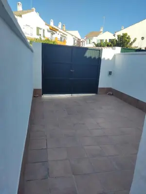 a patio with a black garage door on a white wall at Mi Rinconcito de El Manantial in El Puerto de Santa María