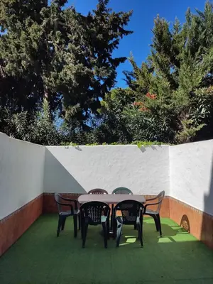 a table and chairs on a patio with trees at Mi Rinconcito de El Manantial in El Puerto de Santa María
