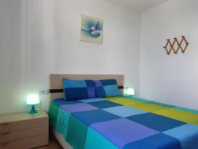 a bedroom with a bed with blue and colorful sheets at Mi Rinconcito de El Manantial in El Puerto de Santa María