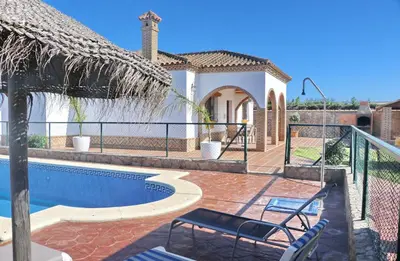 a swimming pool with two chairs and a house at Villa Ureba in Conil de la Frontera