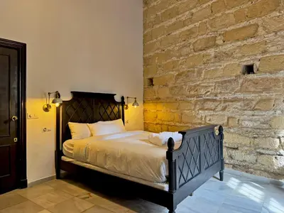 a bed in a room with a brick wall at Palacio Jaramago - Ole Solutions in Jerez de la Frontera