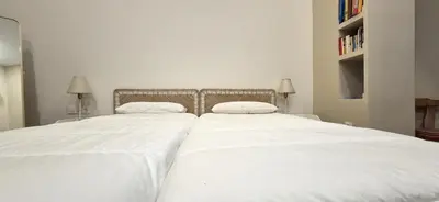 two beds in a bedroom with white sheets at Santa Catalina by Gades Gestión in Cádiz