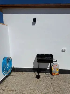 a black grill sitting on a table in front of a wall at Apartamento con piscina y jardín in Chiclana de la Frontera
