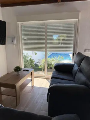 a living room with a couch and a large window at Apartamento con piscina y jardín in Chiclana de la Frontera
