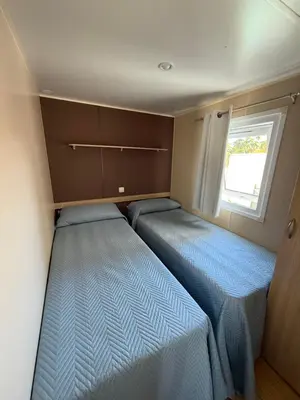 two beds in a small room with a window at Apartamento con piscina y jardín in Chiclana de la Frontera