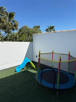 a small playground with a trampoline at Apartamento con piscina y jardín in Chiclana de la Frontera