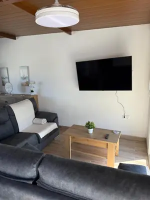 a living room with a couch and a flat screen tv at Apartamento con piscina y jardín in Chiclana de la Frontera