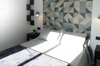 a bedroom with a white bed with a geometric wall at Apartamento - Casa Trufa in Conil de la Frontera