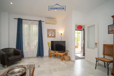 a living room with a tv and a chair at Casa 4 - Capuchinos in Sanlúcar de Barrameda