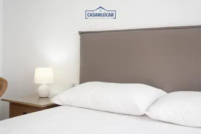 a bedroom with a bed with white pillows at Casa 4 - Capuchinos in Sanlúcar de Barrameda