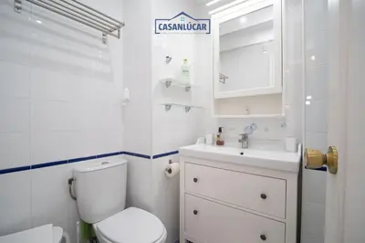 a white bathroom with a toilet and a sink at Casa 4 - Capuchinos in Sanlúcar de Barrameda