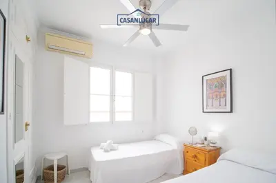 a white room with two beds and a ceiling fan at Casa 4 - Capuchinos in Sanlúcar de Barrameda