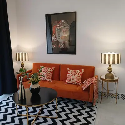 a living room with an orange couch and a table at Beautiful penthouse with terrace next to the Cathedral in Cádiz