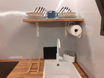 a kitchen with a sink and a shelf with dishes at Casa Flotante El Refugio del Pirata in El Puerto de Santa María